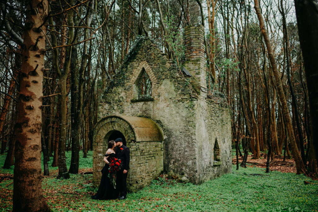 Couple kissing beside a woodland chapel ruin during their Ireland elopement