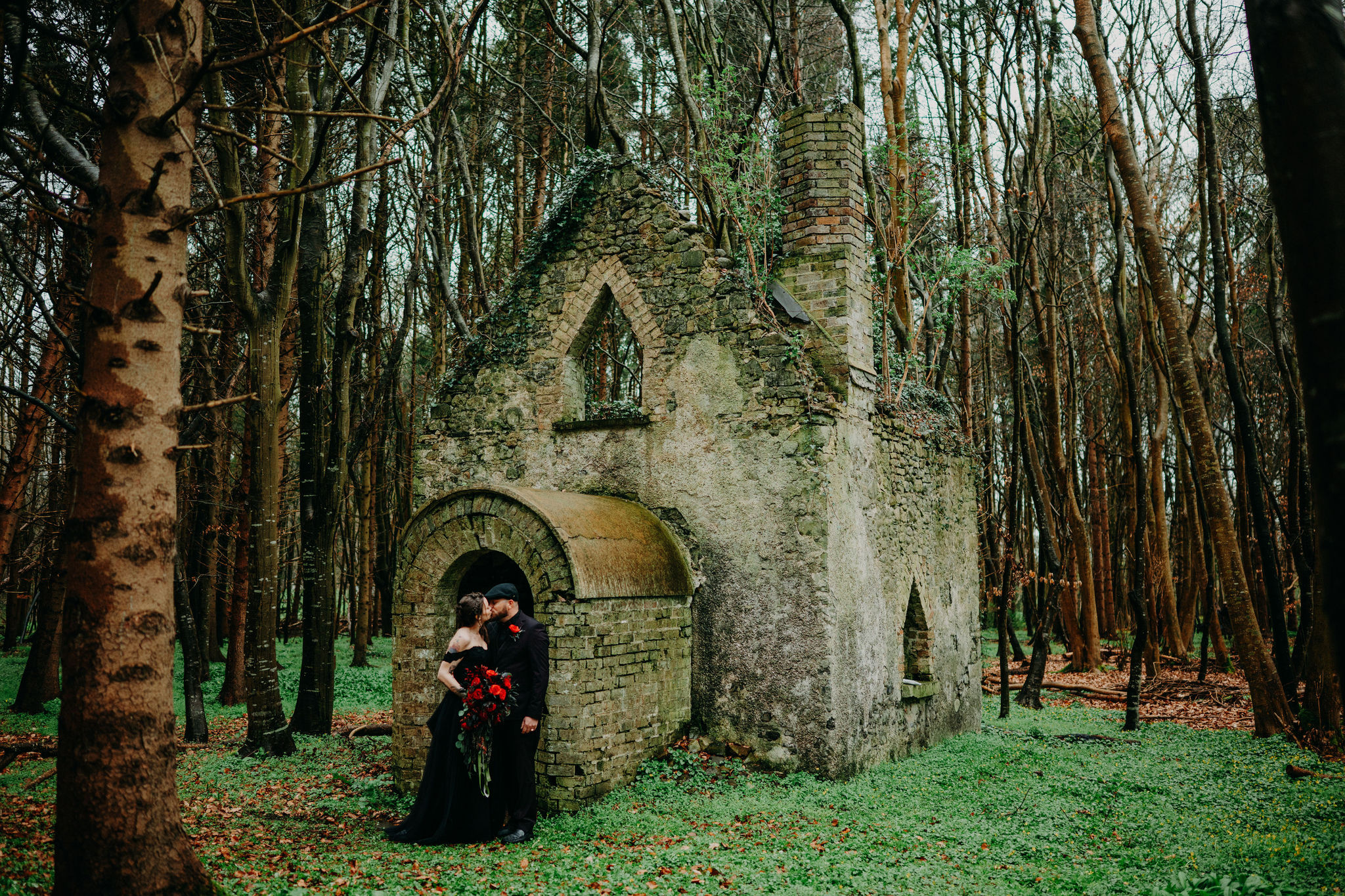 Couple kissing beside a woodland chapel ruin during their Ireland elopement