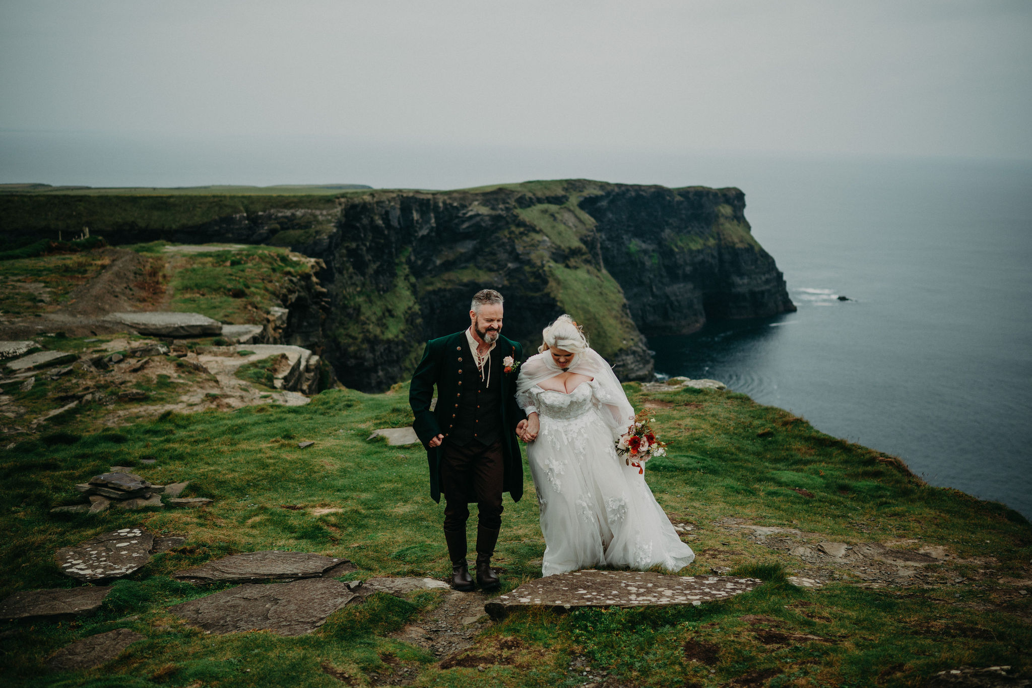 Romantic couple walking beside the Cliffs of Moher during their Ireland elopement wedding at Hags Head.