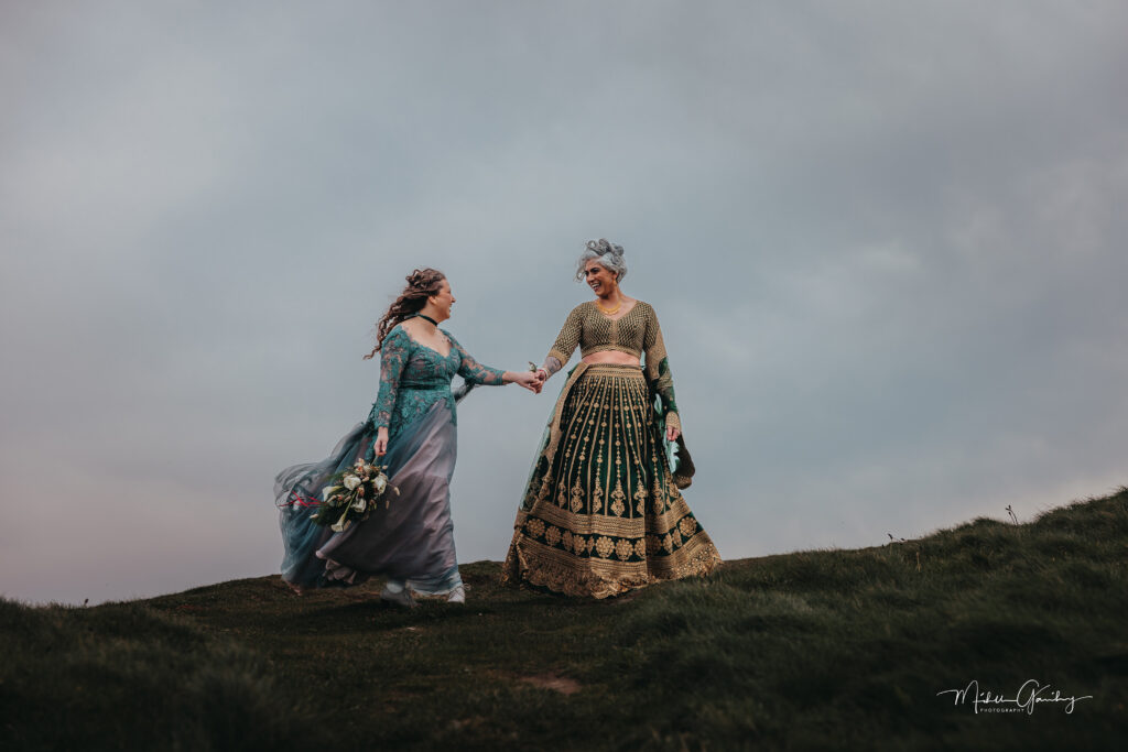 Same-sex couple eloping at Cliffs of Moher Hags Head Ireland holding hands on cliff edge