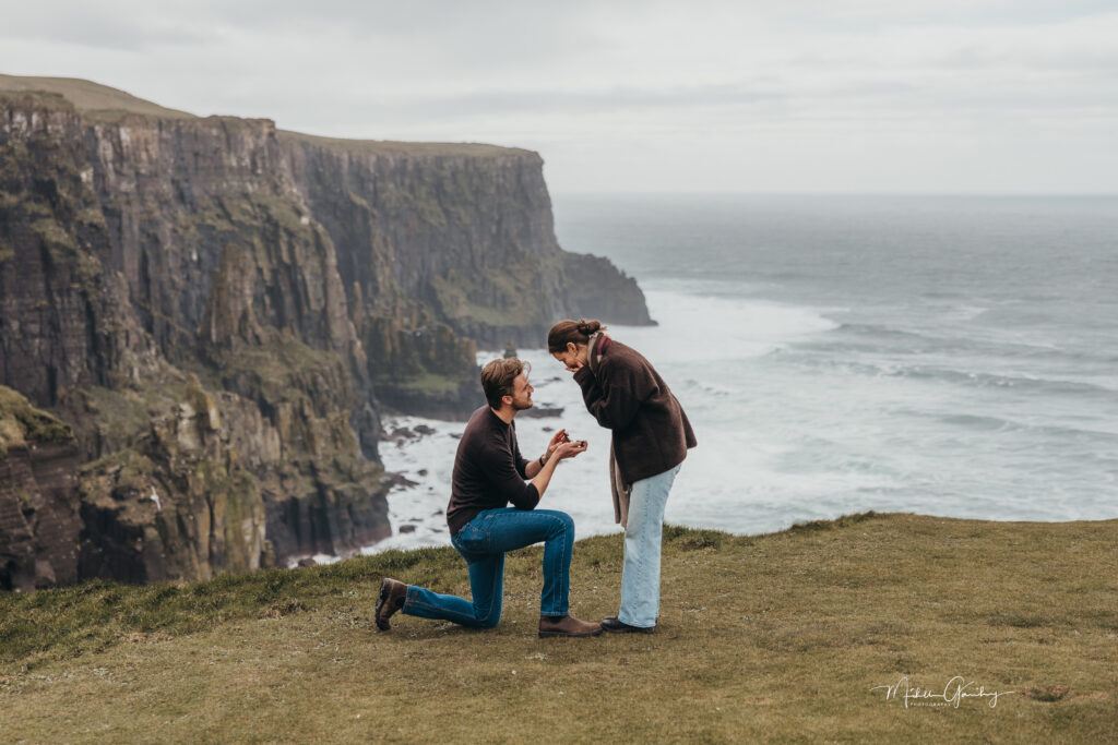 Couple getting engaged at the Cliffs of Moher during a scenic Ireland proposal experience.