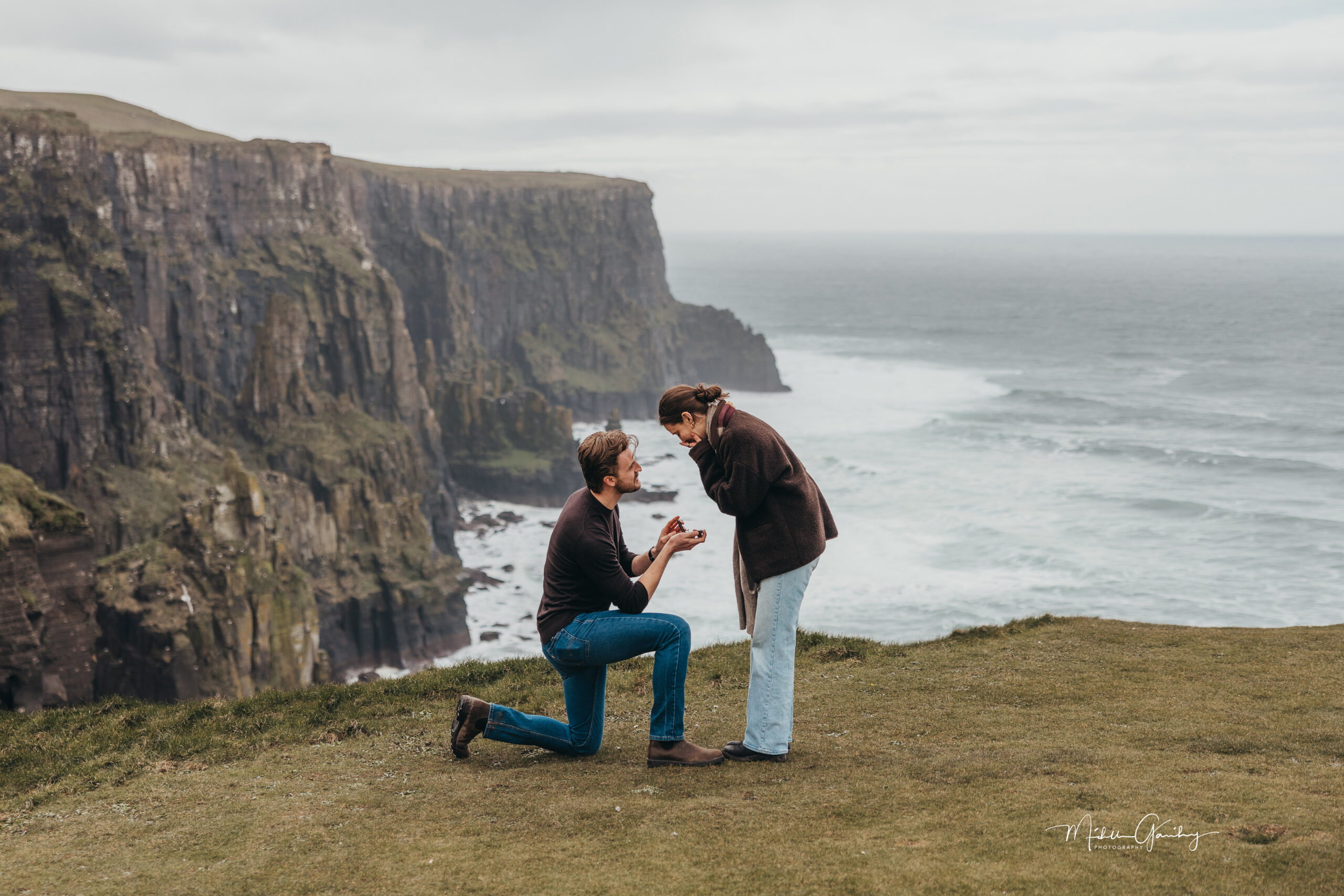 Couple getting engaged at the Cliffs of Moher during a scenic Ireland proposal experience.