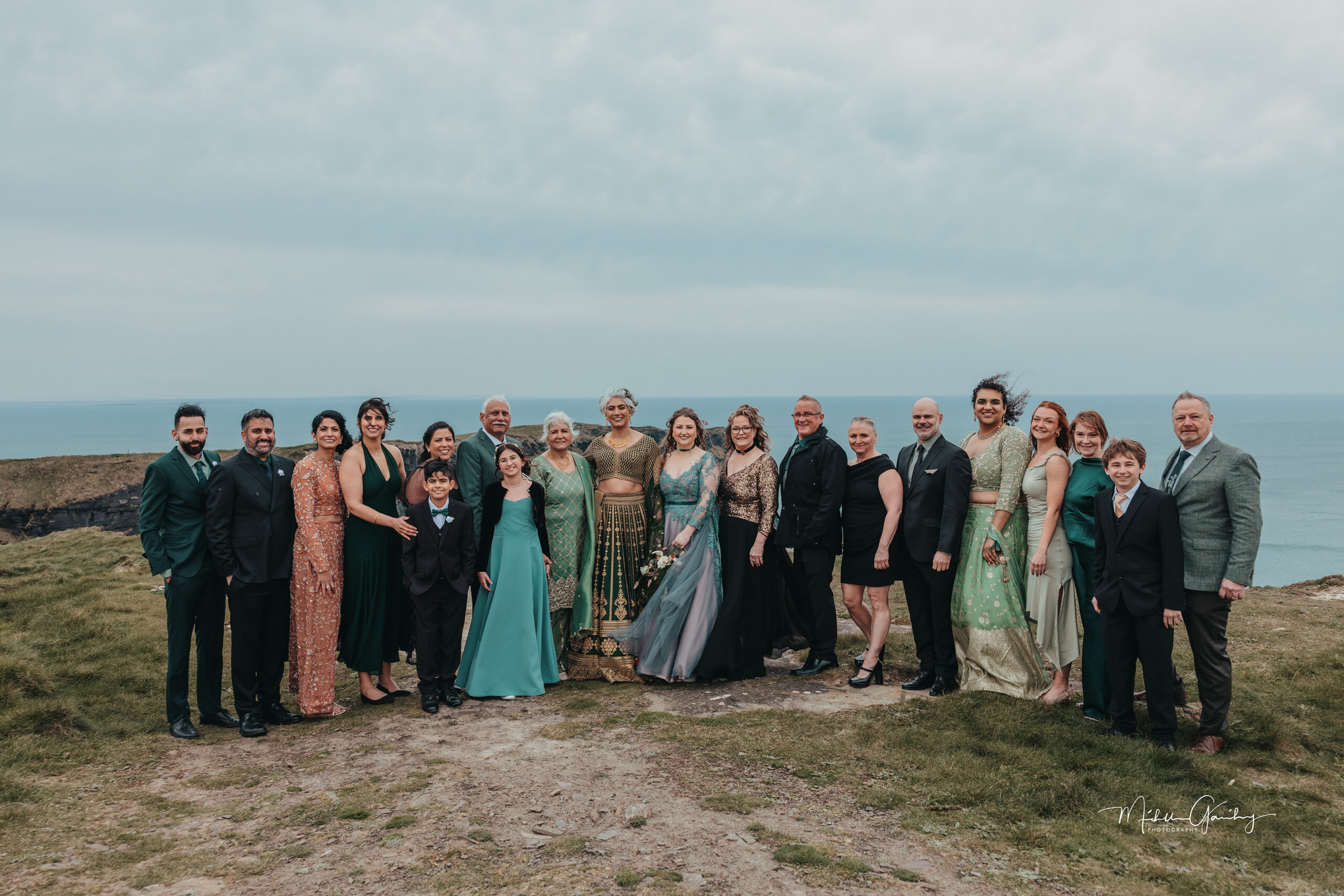 Same-sex wedding group photo with family and friends at the Cliffs of Moher in Ireland.