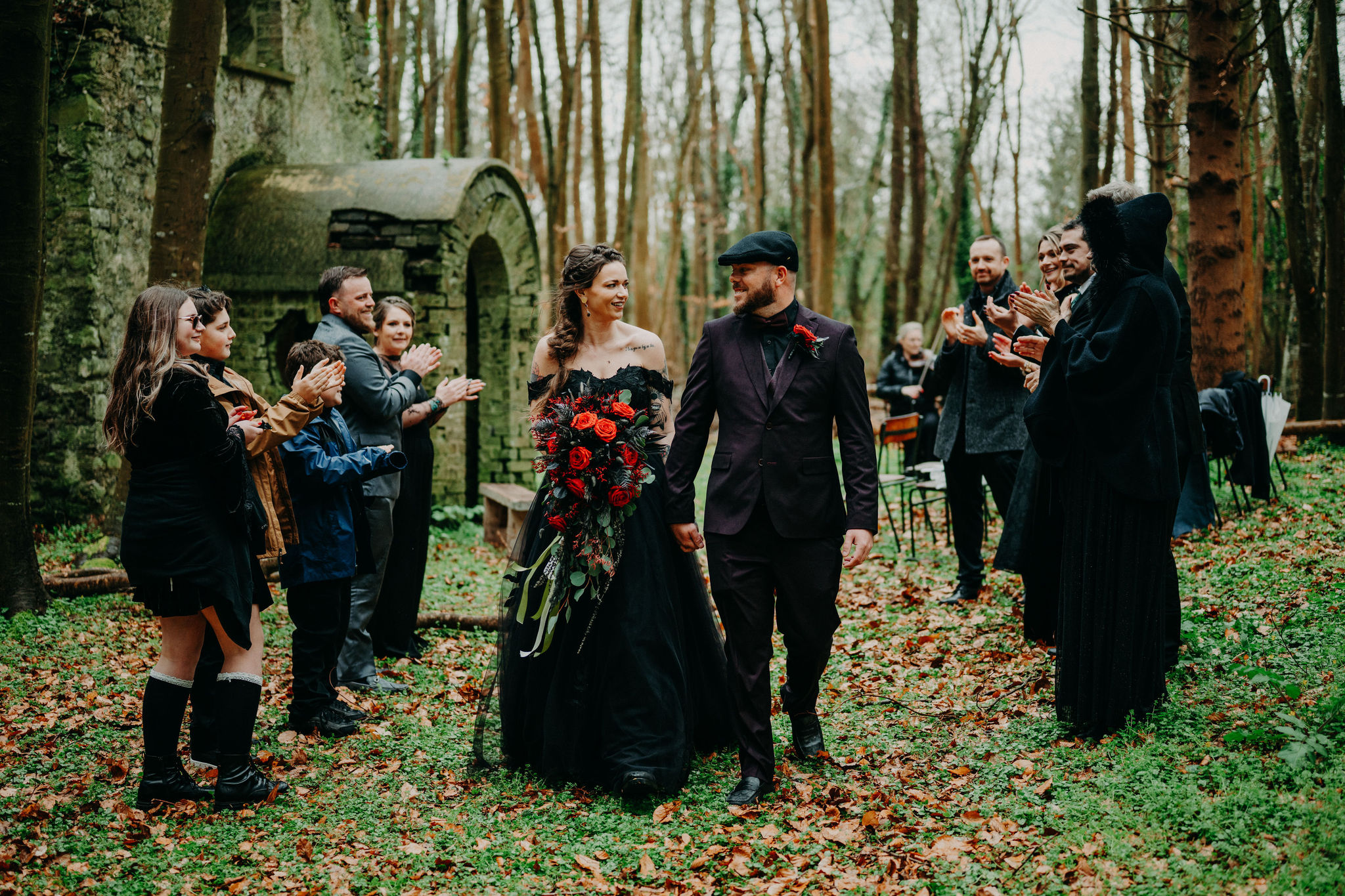 Couple walking hand in hand through guests after a woodland chapel elopement ceremony in Ireland