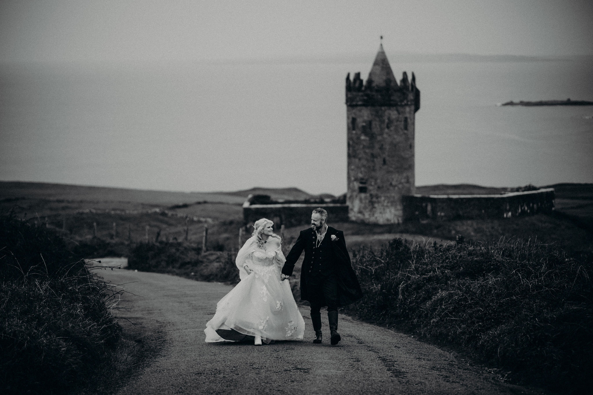 Bride and groom walking near Doonagore Castle during destination wedding in Ireland.