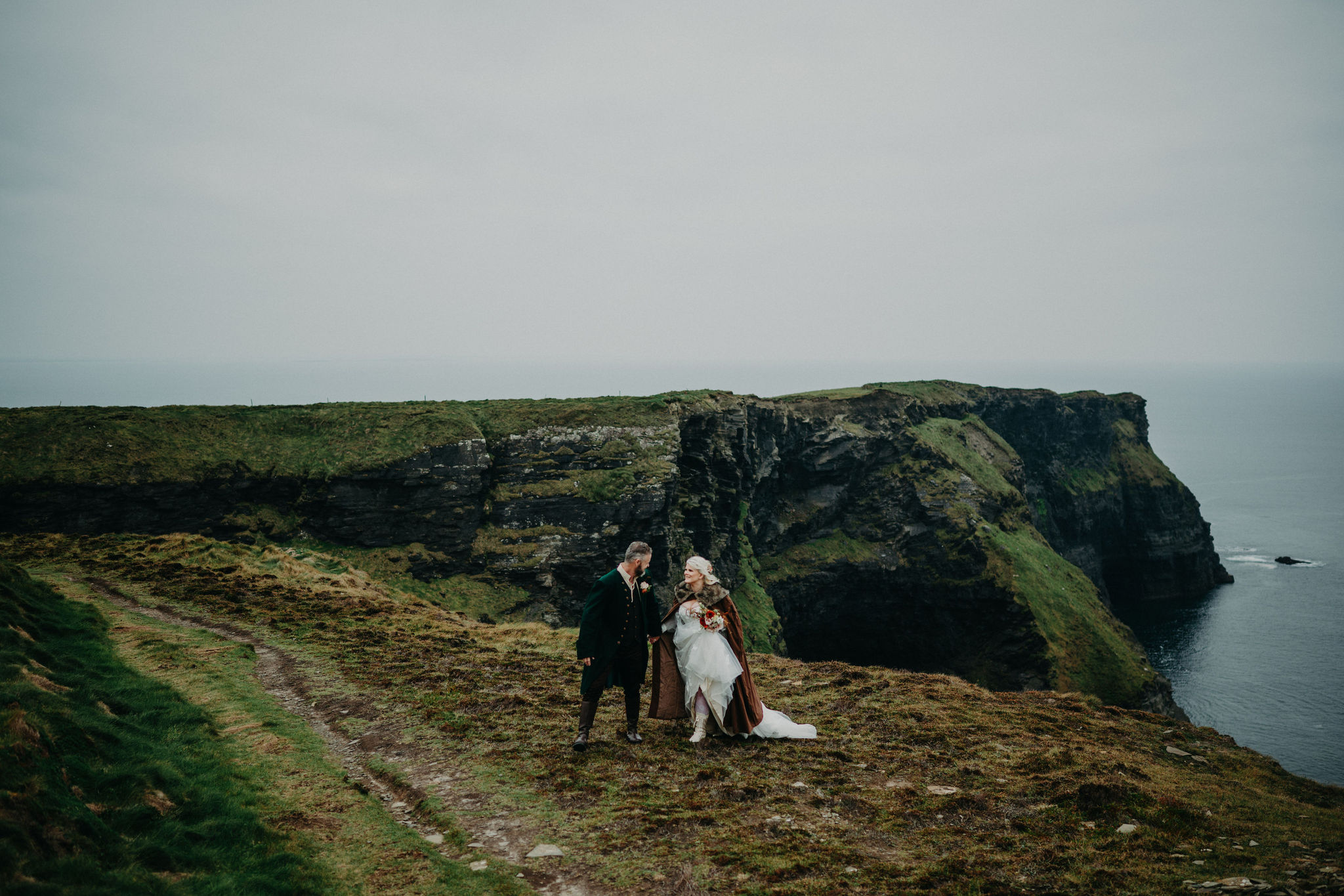 Couple eloping at the Cliffs of Moher in Ireland with dramatic ocean cliff backdrop.