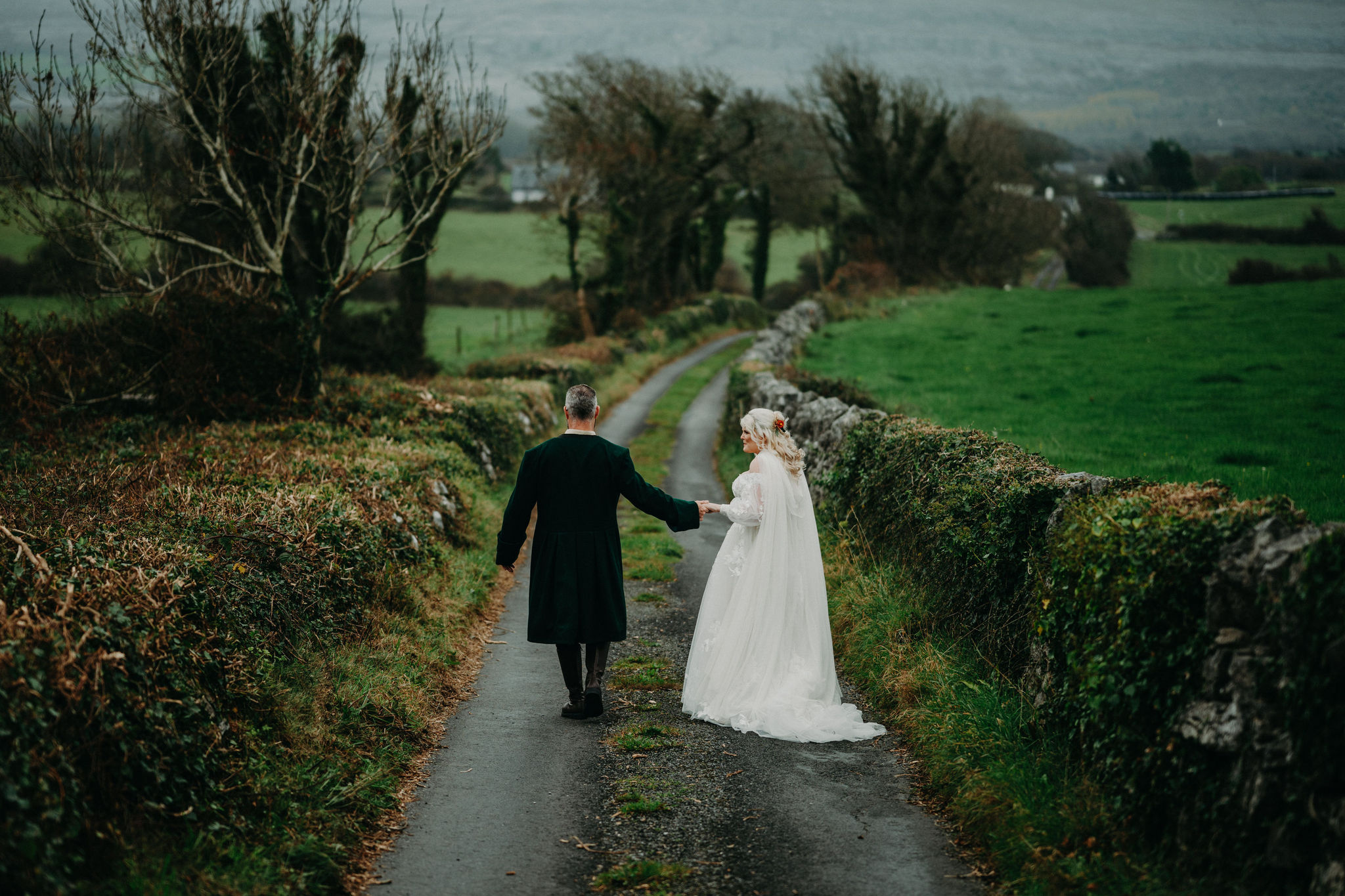 Couple walking hand in hand near Newtown Castle while eloping in Ireland.