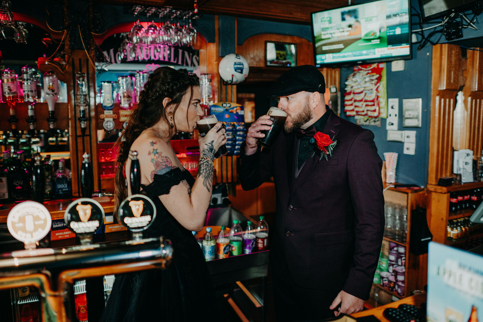 Couple drinking pints of Guinness behind the bar in a traditional Irish pub during their wedding celebration
