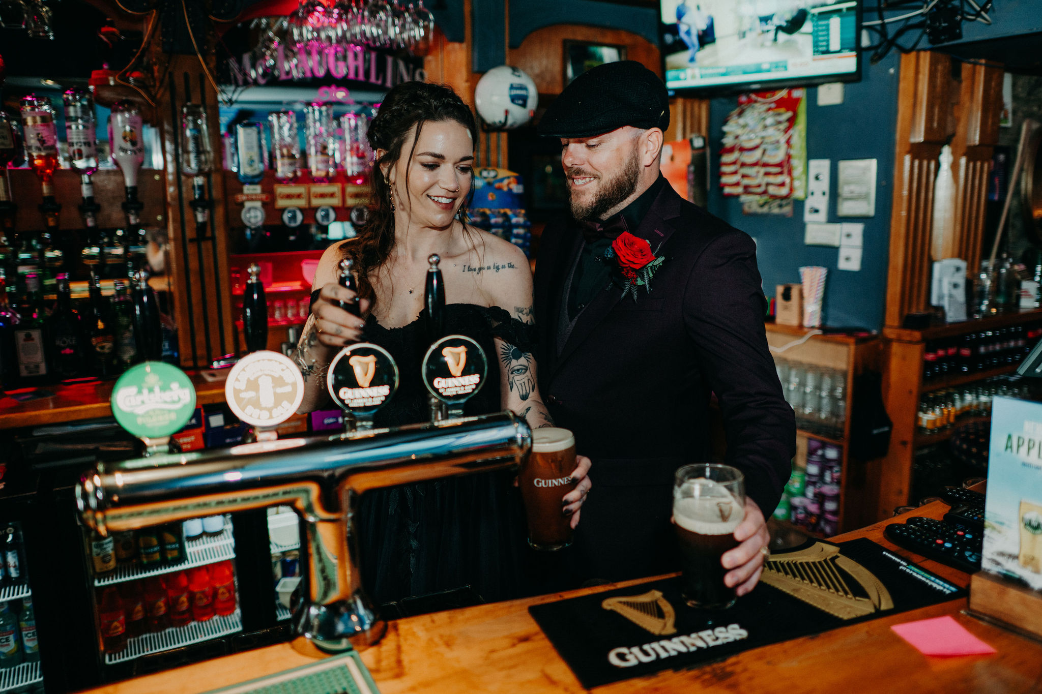 Couple pouring pints of Guinness behind the bar in a traditional Irish pub during their wedding celebration