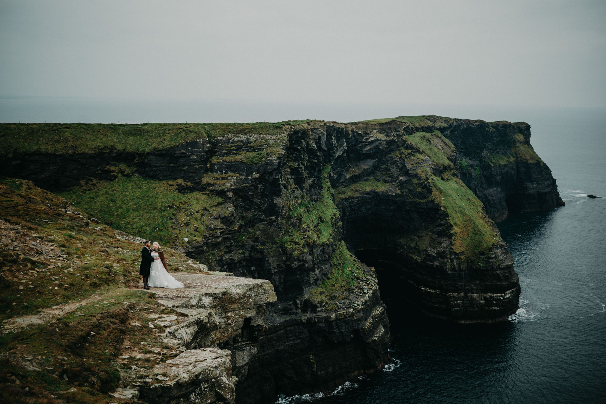 Bride and groom holding hands at the Cliffs of Moher during destination wedding in Ireland.