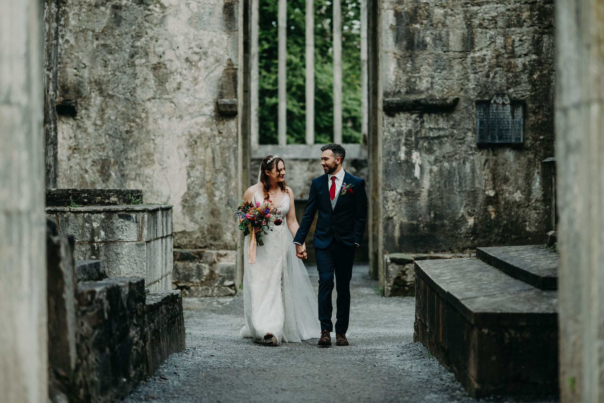 Couple walking through Muckross Abbey cloisters after ceremony