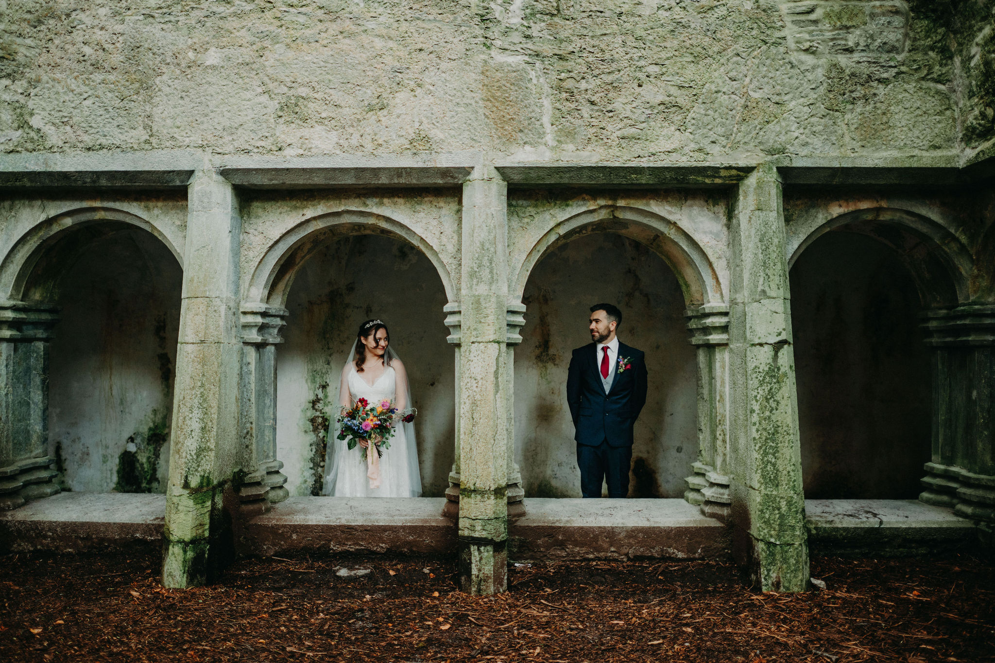 Bride and groom in stone arches at Muckross Abbey