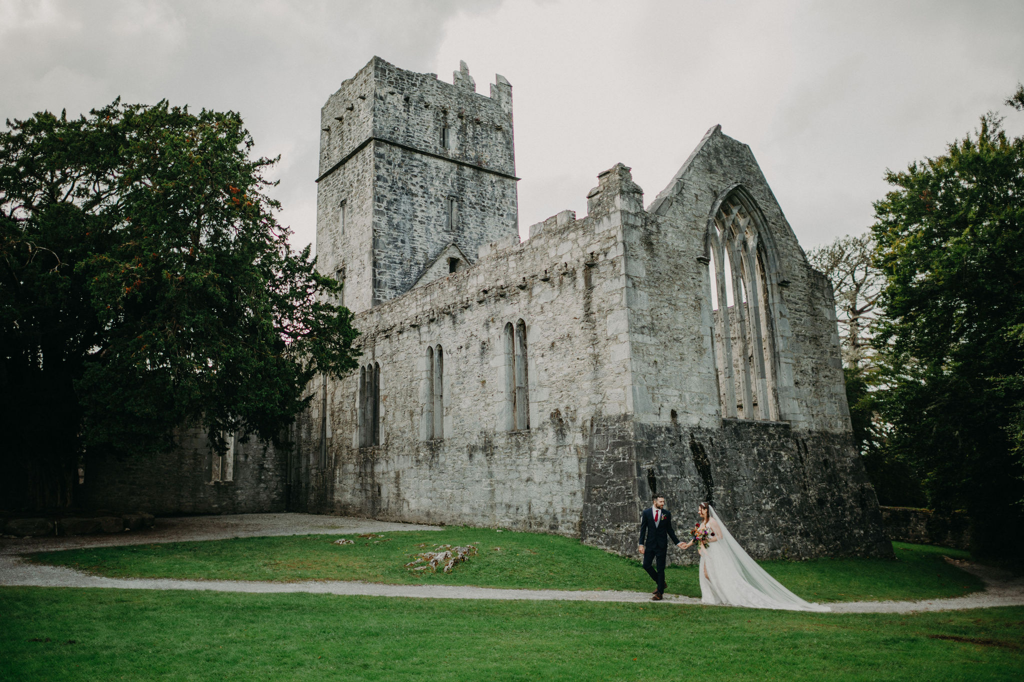 Bride and groom walking beside Muckross Abbey ruins