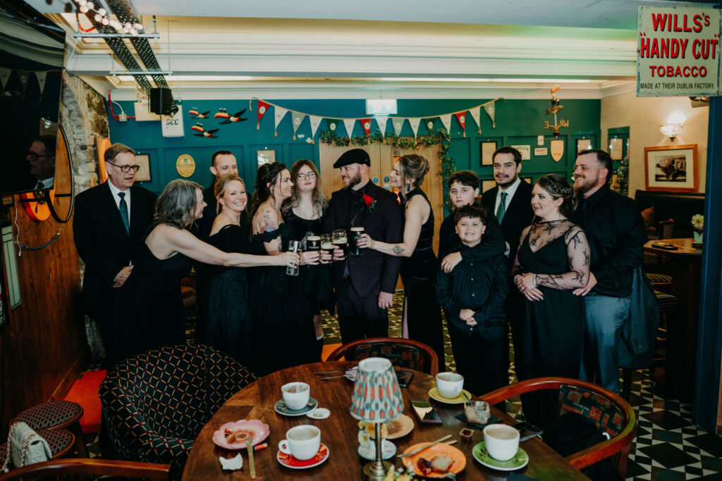 Wedding group celebrating with drinks in a traditional Irish pub during an Ireland destination wedding