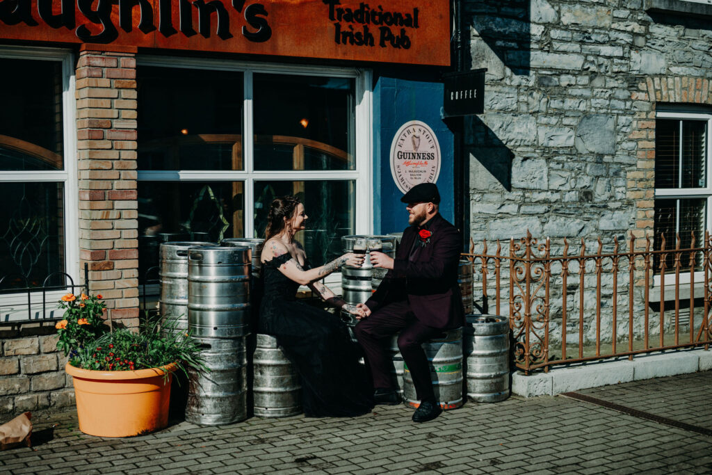 Couple toasting drinks outside a traditional Irish pub during their Ireland elopement.
