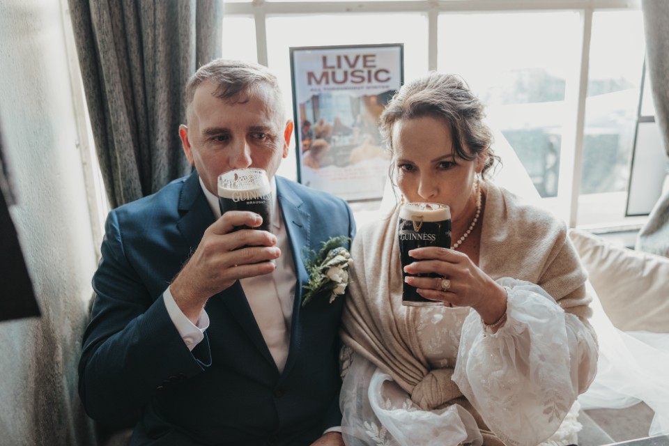 Couple enjoying a Guinness toast after their Ireland elopement celebration in a traditional pub.