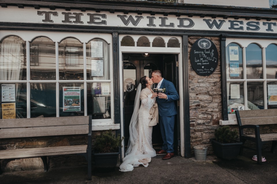 Newlyweds kissing outside a traditional Irish pub after their elopement celebration.