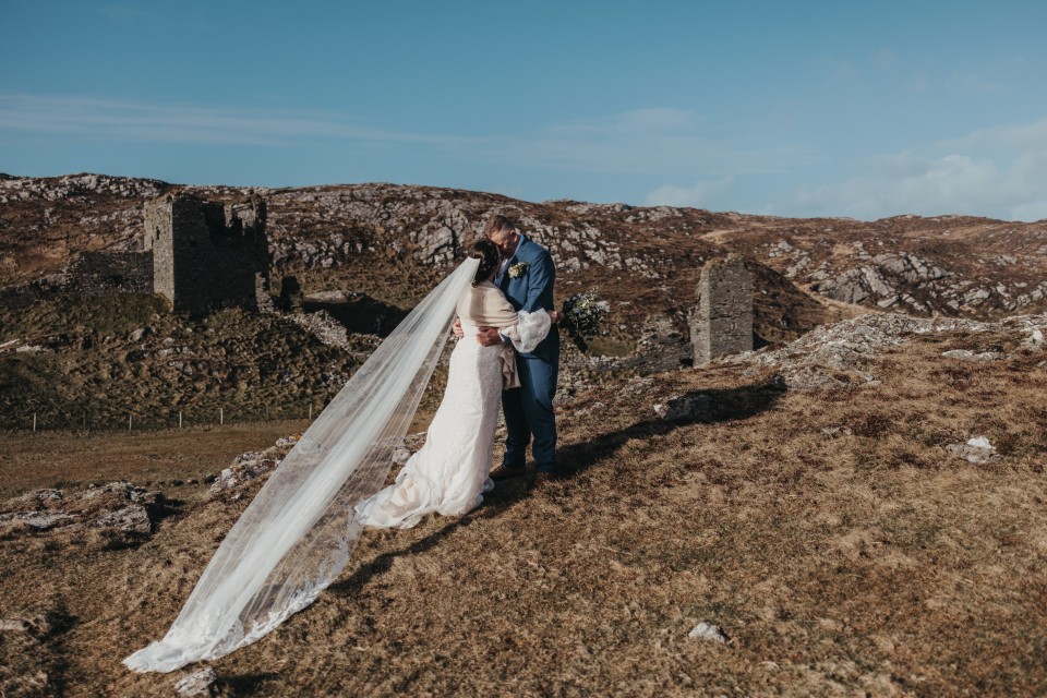 Romantic elopement kiss in the Irish mountains with ancient ruins in the background.
