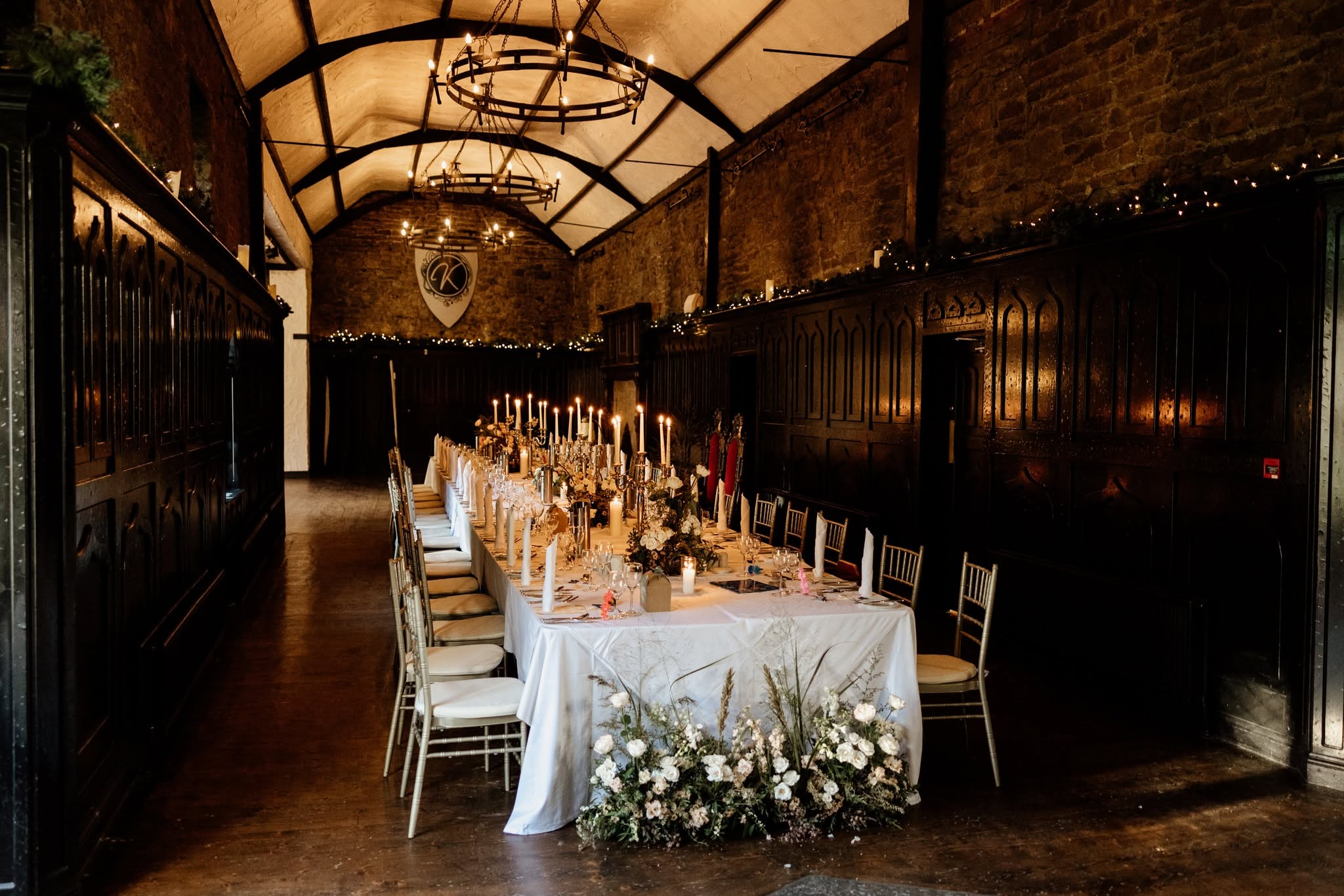 Intimate wedding reception in Ireland with a beautifully decorated long dining table, candles and white flowers in a historic venue.